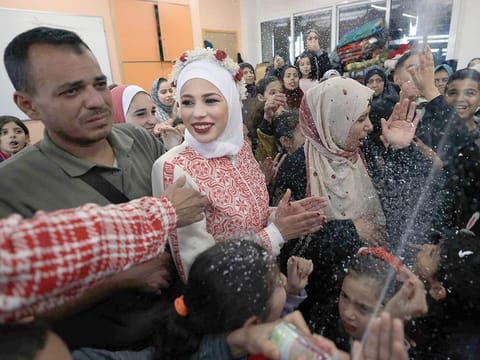 Palestinian newly-wed couple Afnan Jibril (2nd left) and Mostafa Shamlakh are surrounded by guests and relatives during their wedding at the UNRWA School in the al Salam neighbourhood of Rafah, southern Gaza Strip, on January 12, 2024, amid continuing battles between Israel and the Hamas. 