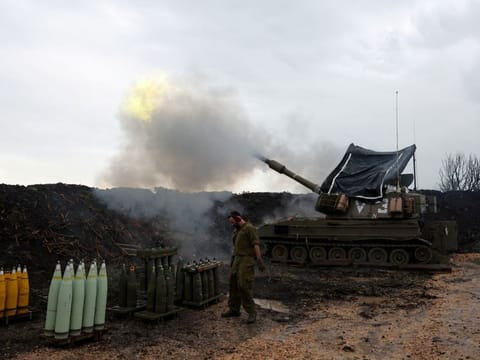 An Israeli soldier stands by, as a mobile artillery unit fires, near the Israel-Lebanon border, in northern Israel.
