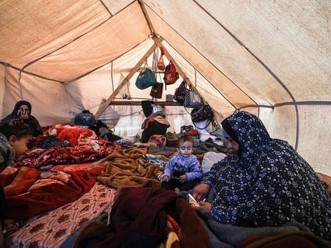 Members of a displaced Palestinian family sit inside a tent at a makeshift camp in Rafah in the southern Gaza 