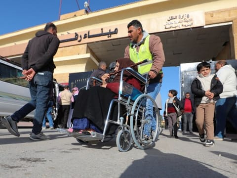 A man assists a Palestinian woman in a wheelchair, at the Rafah border crossing between Egypt and the Gaza Strip, amid the ongoing conflict between Israel and Palestinian Islamist group Hamas, in Rafah, Egypt, on February 1, 2024.  