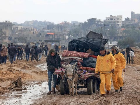 Palestinians, some wearing Hazmat suits left over from the Coronavirus pandemic to keep warm, transport some of their belongings as the flee Khan Yunis in the southern Gaza Strip further south on February 2, 2024, as battles between Israel and the Hamas militant group continue. 