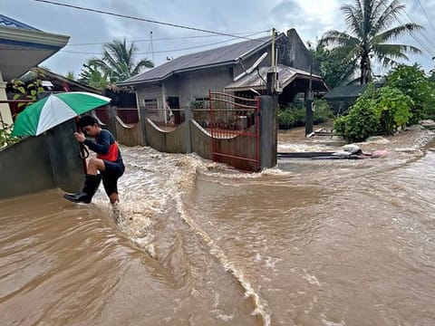 A man wades through floodwaters brought about by heavy rains at a residential neighbourhood in Propseridad town, Agusan del Sur province on southern Mindanao island.