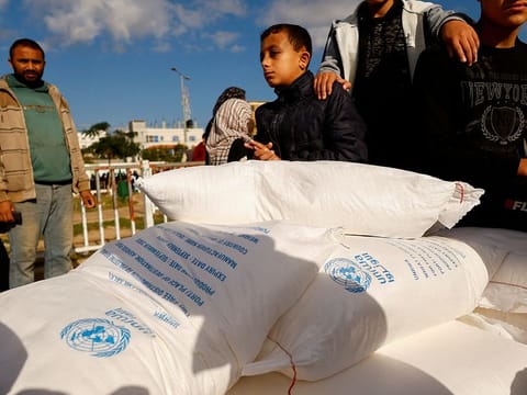 Palestinians receive flour bags distributed by UNRWA in Rafah, in the southern Gaza Strip 