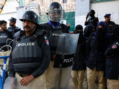 Police officers stand guard during a protest by the supporters of the former Prime Minister Imran Khan's party Pakistan Tehreek-e-Insaf (PTI) and the religious and political party Jamat-e-Islami (JI) demanding free and fair results of the elections, outside the provincial Election Commission of Pakistan (ECP) building in Karachi.