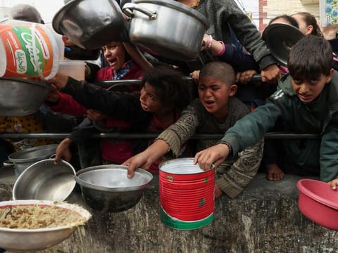 Palestinian children wait to receive food cooked by a charity kitchen amid shortages of food supplies, as the ongoing conflict between Israel and the Palestinian Islamist group Hamas continues, in Rafah, in the southern Gaza Strip, on February 13, 2024.  