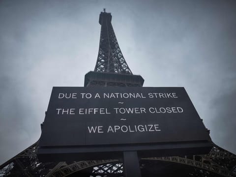 A board informs visitors that the Eiffel Tower is closed during the second week of the French school holidays.  