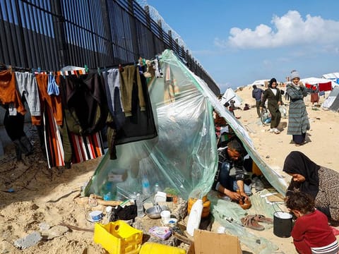 Displaced members of Palestinian Abu Mustafa family, who fled their house due to Israeli strikes, prepare food as they shelter at the border with Egypt, in Rafah in the southern Gaza Strip, February 10, 2024. 
