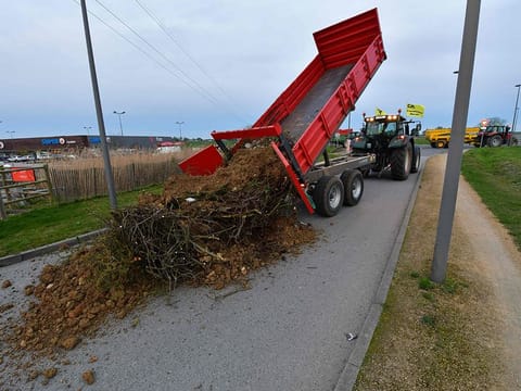 Farmers of the CR86 union (Coordination rurale 86) unload a skip of garbage and debris in front of a supermarket in Loudun, western France, on February 21, 2024. French farmers have resumed their actions ahead of President Emmanuel Macron's visit to a high-tension Salon de l'Agriculture (Agriculture Fair) on February 24, 2024. 