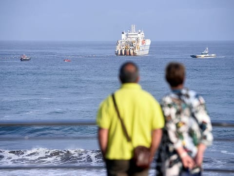 A couple observe a cable laying ship at Arrietara beach, near Bilbao, northern Spain, June 13, 2017, as Facebook Inc. and Microsoft Corp. join forces to build an underwater fiber optic cable across the Atlantic Ocean, linking Europe and the USA. 
