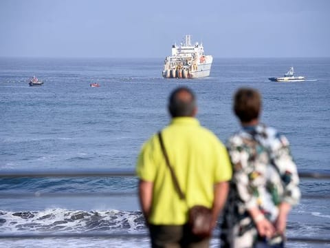 A couple observe a cable laying ship at Arrietara beach, near Bilbao, northern Spain, June 13, 2017, as Facebook Inc. and Microsoft Corp. join forces to build an underwater fiber optic cable across the Atlantic Ocean, linking Europe and the USA. 