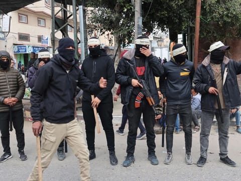 Masked members of the so-called "Popular Committees of Protection", some armed with batons, patrol the streets of Gaza's southern city of Rafah on March 6, 2024.  