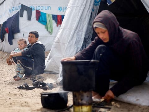 Displaced Palestinian children, who fled their houses due to Israeli strikes, sit at a tent camp, amid the ongoing conflict between Israel and the Palestinian Islamist group Hamas, in Rafah in the southern Gaza Strip, March 6, 2024. 
