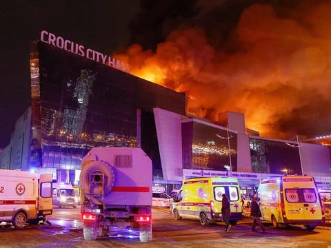 Vehicles of Russian emergency services are parked near the burning Crocus City Hall concert venue following a reported shooting incident, outside Moscow, on March 22, 2024. 