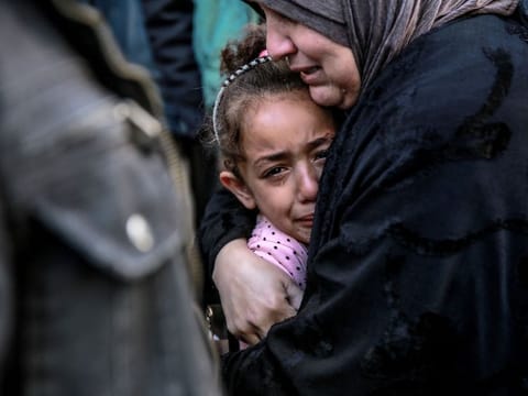 A Palestinian woman holds a child as they mourn their relatives killed in Israeli bombardment in front of the morgue of the Al Shifa hospital in Gaza City.