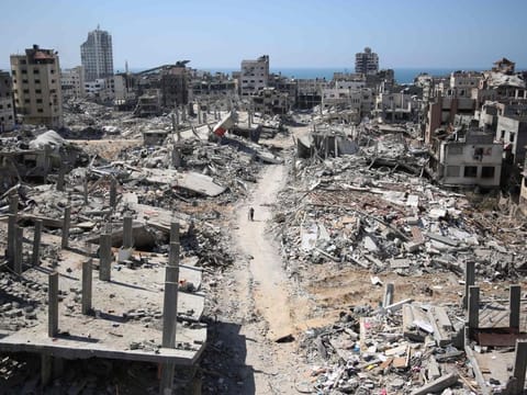 A man pushes a bycicle along as he walks amid building rubble in the devastated area around Gaza's Al Shifa hospital on April 3, 2024.