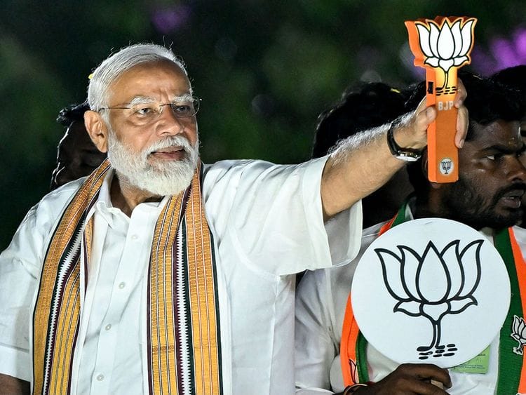 Modi holds the party symbol during a road show at an election campaign held ahead of the country's upcoming general elections, in Chennai on April 9, 2024.  