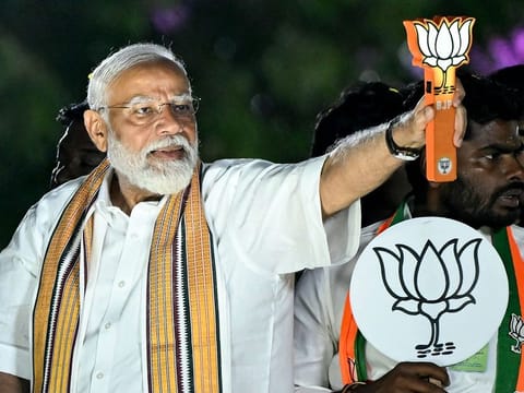 Modi holds the party symbol during a road show at an election campaign held ahead of the country's upcoming general elections, in Chennai on April 9, 2024.  