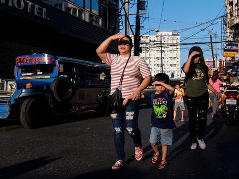 People use their hands to shield their faces from the sun during a hot day, in Manila, Philippines.