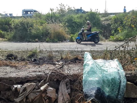 A motorist rides a motorcycle past the site of an Israeli strike on a vehicle in the Adloun plain area, between Lebanon's southern cities of Sidon and Tyre, on April 23, 2024.  