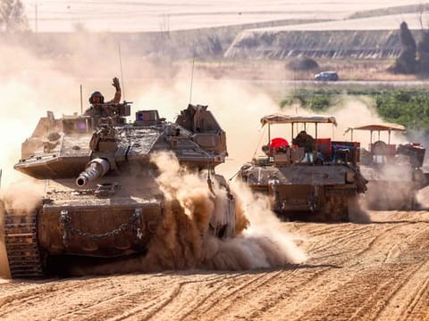 Israeli army battle tanks move near the border with the Gaza Strip at a location in southern Israel.