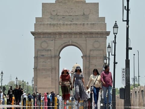 People walk on Kartavya Path while covering themselves to protect from the scorching heat on a hot summer day, in New Delhi on Monday. 