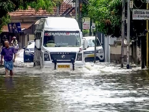  Commuters ply through a waterlogged area after heavy rains lashed the city, at Mukkolackal, in Thiruvananthapuram on Sunday. 