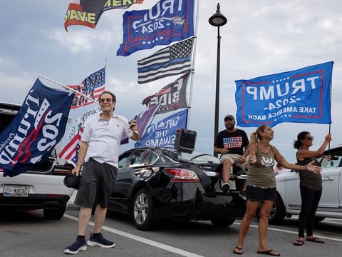Supporters hold placards and flags following the announcement of the verdict in former US President Donald Trump's criminal trial over charges that he falsified business records to conceal money paid to silence porn star Stormy Daniels in 2016, outside Trump’s Mar-a-Lago resort in Palm Beach, Florida, on May 30, 2024. 