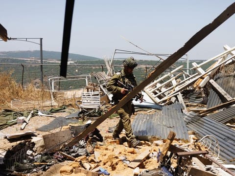 An Israeli soldier at the site of an Hezbollah anti-tank missile direct hit on a house near the Lebanon border in Moshav Shtula, northern Israel, on Wednesday, June 19, 2024.  