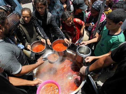 Palestinians gather to receive food cooked by a charity kitchen, amid shortages of aid supplies, as the conflict between Israel and Hamas continues, in Khan Younis, in the southern Gaza Strip.