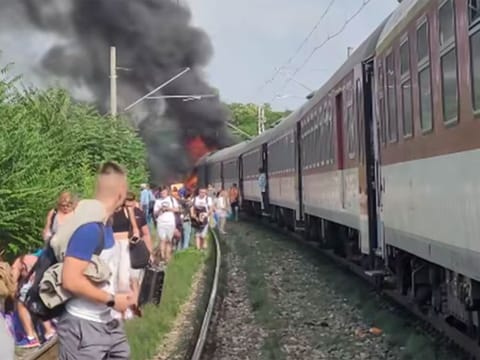 Passengers alongside a train in flames.
