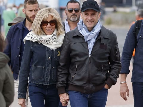 France's President Emmanuel Macron (R) and his wife first lady Brigitte Macron (L) walk along the beach during an air show in Le Touquet-Paris-Plage, northern France, on June 29, 2024. 
