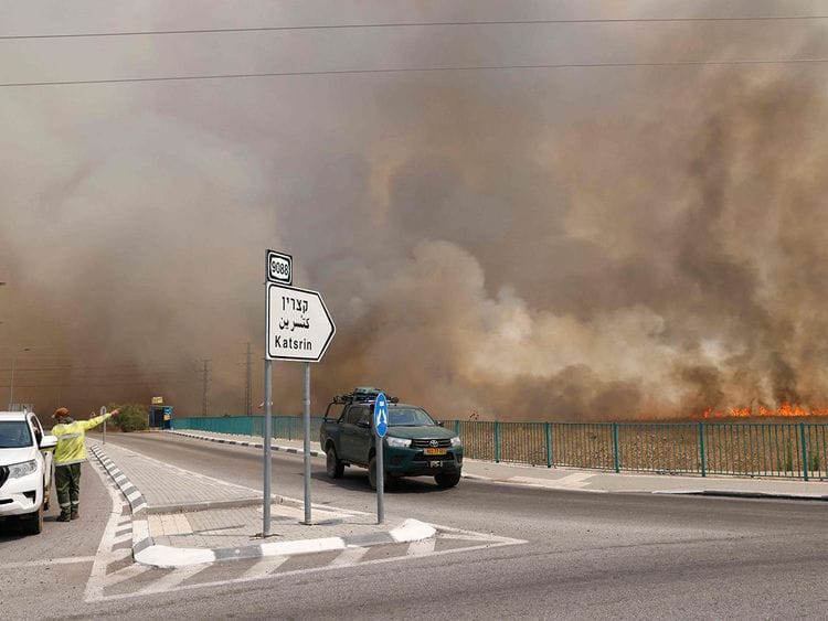  Vehicles leave an area engulfed by smoke from fires after rockets launched from southern Lebanon hit areas in the Israeli-annexed Golan Heights, on July 4, 2024. 