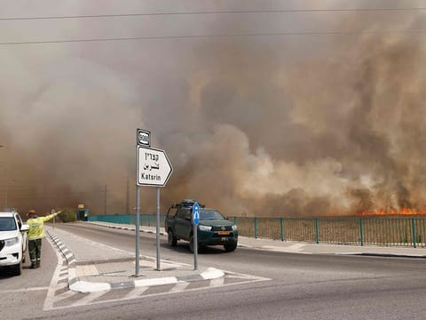  Vehicles leave an area engulfed by smoke from fires after rockets launched from southern Lebanon hit areas in the Israeli-annexed Golan Heights, on July 4, 2024. 