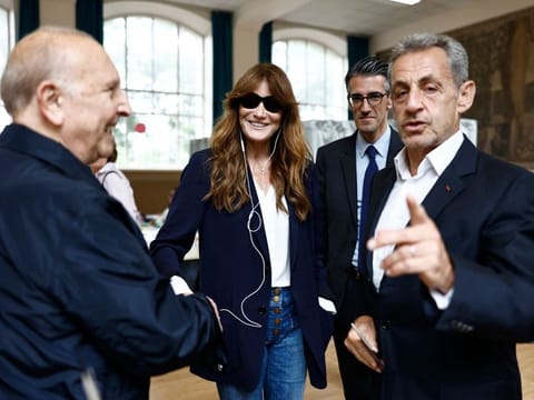 French singer Carla Bruni with Sarkozy and the Mayor of Paris' 16th district Jeremy Redler in a polling station during the vote of the second round of France's legislative election in Paris, on July 7, 2024.  