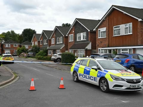 A police officer stands guard behind a cordon at Ashley Close in Bushey in the borough of Hertfordshire, north of London, on July 10, 2024 after a triple "crossbow attack" murder.  