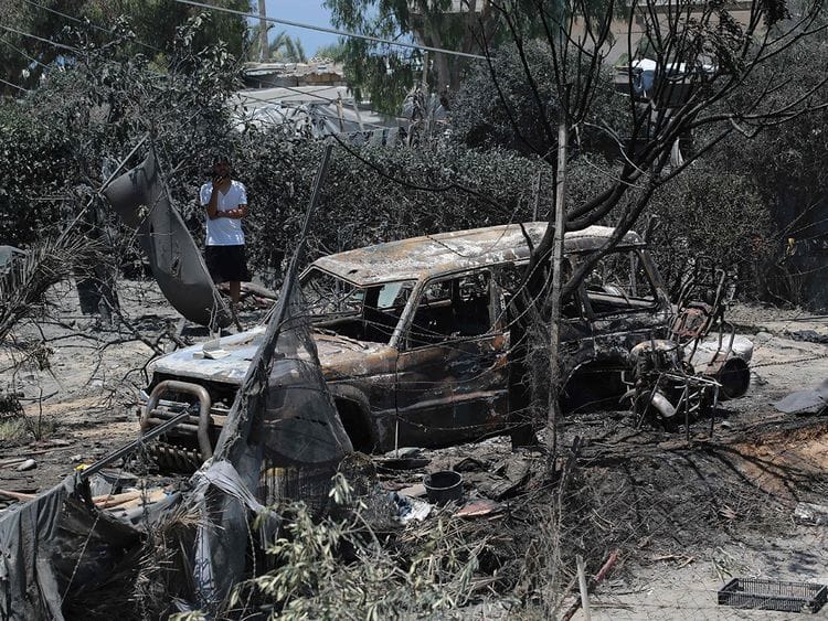 A Palestinian man looks at a burnt out vehicle following an Israeli military strike