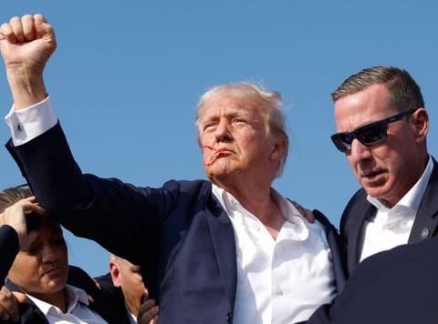 Trump pumps his fist as he is rushed offstage during a rally on July 13, 2024 in Butler.