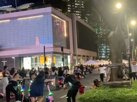 A fenced-off street forms part of the night scene at the Bonifacio Global City in Manila, filled with young people on e-scooters and bikes.