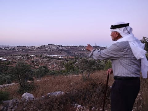 Olayan Olayan, who was born in the village of Battir in 1941, overlooks a valley in which a new Israeli settlers outpost is built, as pictured from Battir, a Unesco heritage village in the occupied West Bank south of Jerusalem, on July 8, 2024.  