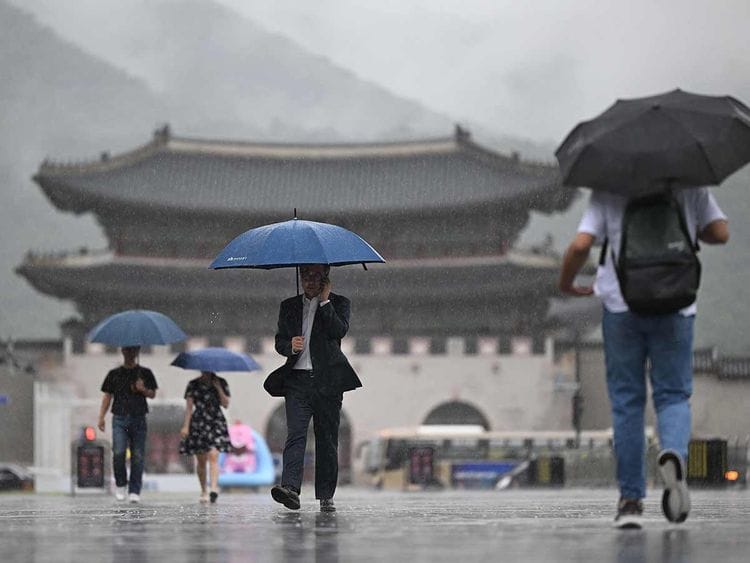 People hold umbrellas as they walk in the central Gwanghwamun square 