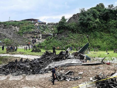 Rescuers and officials stand at the crash site after a Saurya Airlines' plane crashed during takeoff at the Tribhuvan International Airport in Kathmandu on July 24, 2024. 