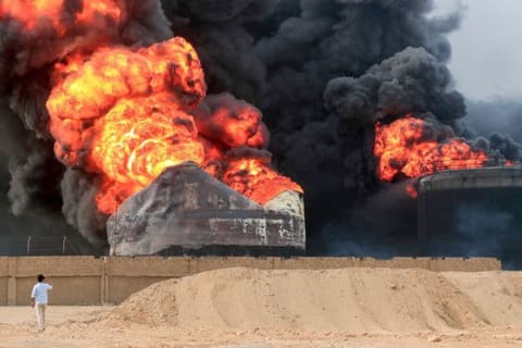 A man takes pictures of a raging fire at oil storage tanks a day after Israeli strikes on the port of Yemen's Al Houthi-held city of Hodeida on July 21, 2024.  