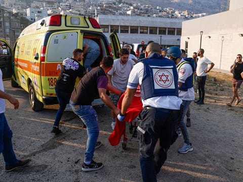 Israeli security forces and medics transport casualties along with local residents, at a site where a reported strike from Lebanon fell in Majdal Shams village in Golan area on July 27, 2024. 