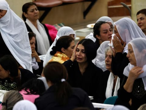 Druze women mourn near the coffins of loved ones after a reported strike from Lebanon fell in Majdal Shams village in the Israeli-annexed Golan area on July 28, 2024.  