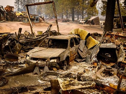 A burned vehicle smolders in the Paynes Creek area of unincorporated Tehama County, California, during the Park fire on July 27, 2024. 