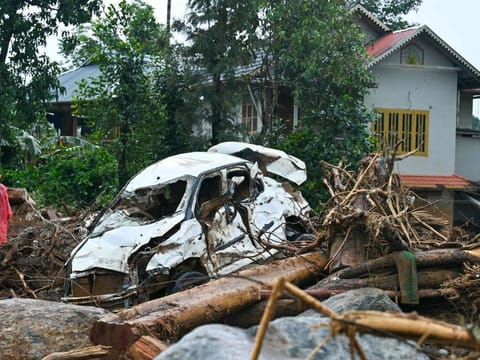 A man walks past a damaged vehicle after the landslides in Wayanad on August 1, 2024. Indian rescue crews scoured mud-caked tea plantations and villages on August 1 with little hope of finding more survivors from landslides that killed around 200 people. (Photo by Idrees MOHAMMED / AFP)