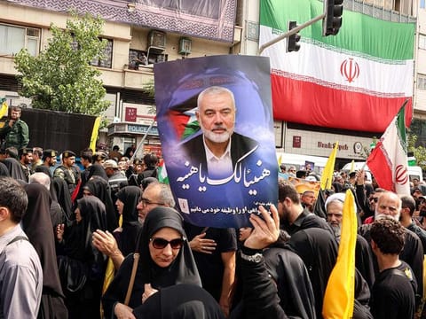 Iranians hold portraits of late Hamas leader Ismail Haniyeh during his funeral procession, in Tehran, on August 1, 2024. 