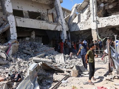 Palestinians check the damage in the Al Zahra school used as a refuge by displaced Palestinians following an Israeli strike, in the Shujaiya neighbourhood of Gaza 