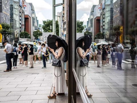 A woman stands with an umbrella on a hot day in Ginza district of Tokyo on August 9, 2024. 