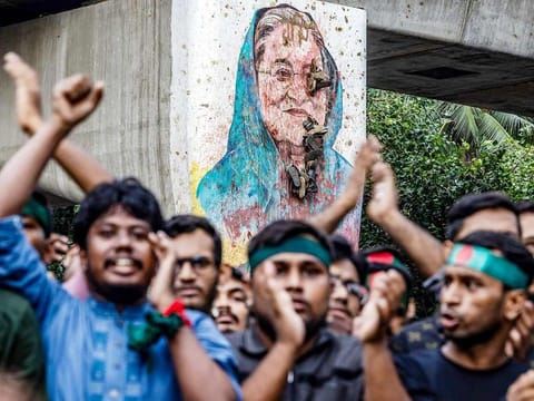 Students chant slogans near a vandalised mural of Bangladesh's ousted Prime Minister Sheikh Hasina, during a protest demanding accountability and trial against Hasina, near Dhaka University in the capital on August 12, 2024. 